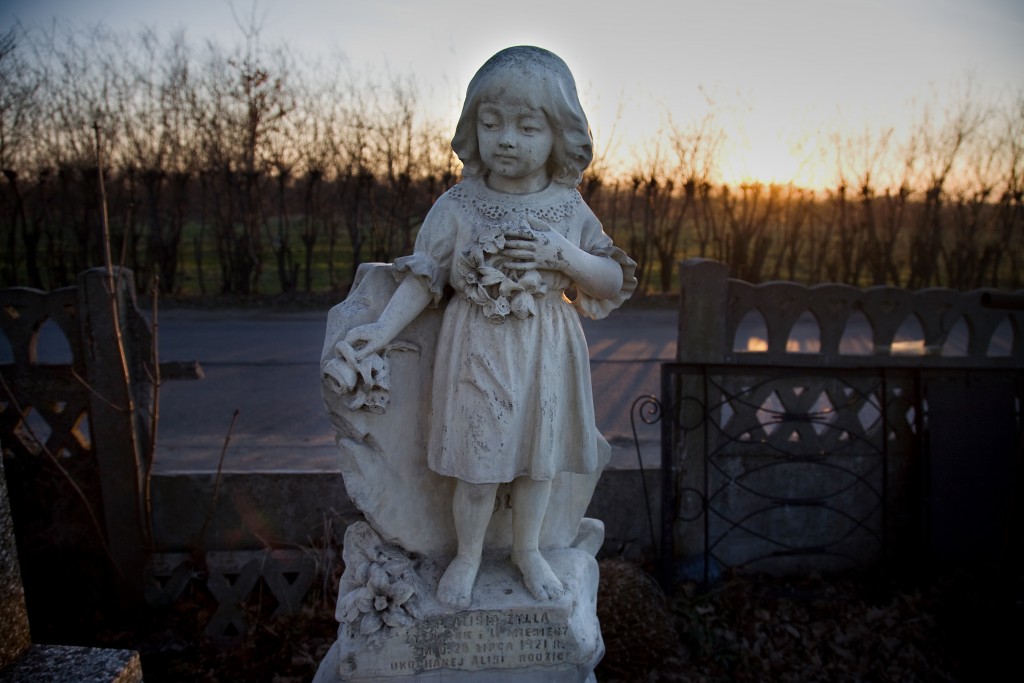 Zdjęcie figurki dziewczynki na cmentarzu.